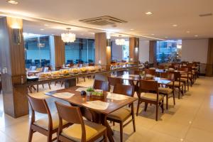 a restaurant with wooden tables and chairs and windows at Rede Andrade Barravento in Ilhéus