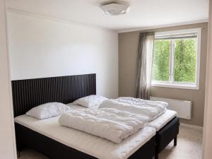 a bedroom with a bed with white sheets and a window at Solbacka apartments Norr - Panorama view in Södra Ås