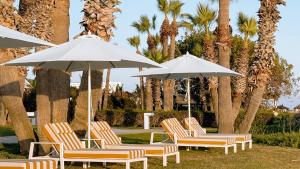 a group of chairs and umbrellas in a park at Imperial Island by Louis Hotels in Yeroskipou