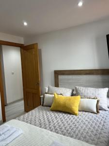 a bedroom with a large bed with two yellow pillows at El Encanto de Sixto in Santa Marta de Ortigueira