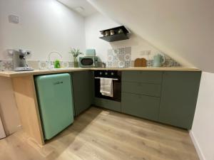 a kitchen with green cabinets and a stove at Amelia in Saint-Aignan