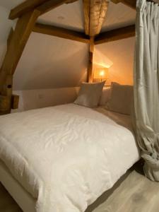 a bed with white sheets and curtains in a room at Amelia in Saint-Aignan