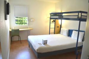 a bedroom with a bunk bed and a desk at Ibis Budget Agen in Le Passage