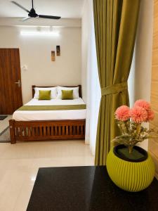 a bedroom with a bed and a vase with flowers on a table at Krishna Theeram 150m from Temple in Guruvāyūr
