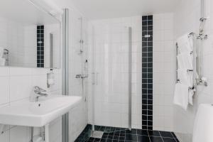 a white bathroom with a sink and a shower at Hotel Gyllene Uttern in Gränna