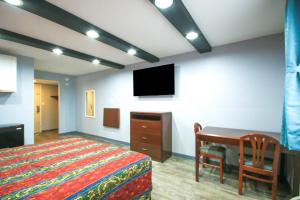 a bedroom with a bed and a desk and a tv at Marshall Lodge By OYO Hwy 65 in Marshall