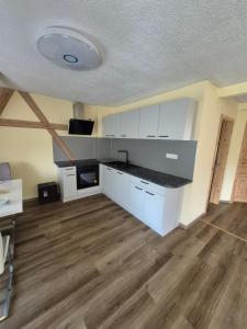 a kitchen with white cabinets and a wooden floor at Pension am Lindenbaum in Kirnitzschtal