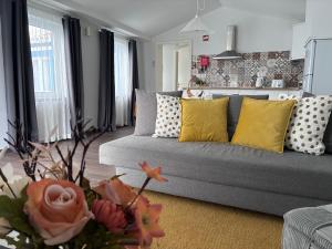 a living room with a gray couch with yellow pillows at A Casinha in Angra do Heroísmo +2 photos