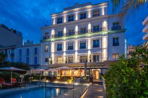 a white building with a pool in front of it at Hôtel Le Canberra in Cannes
