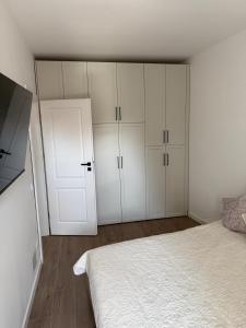 a bedroom with a bed and white cabinets and a door at Aria & Boris Apart Kogalniceanu in Oradea