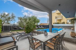 a patio with tables and chairs and a swimming pool at Villa Collis in Makarska