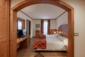 a bedroom with a large bed and a television at Hotel Primiero in Tonadico