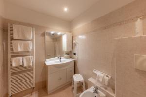 a white bathroom with a sink and a toilet at Hotel Primiero in Tonadico +47 photos