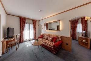 a living room with a red couch and a television at Hotel Primiero in Tonadico