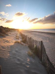 a fence on a beach with the sun setting at La Petite Escale in Lunel