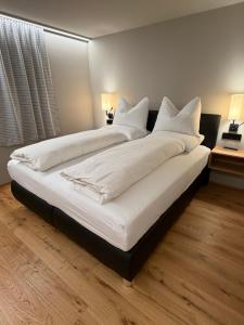 a large bed with white sheets and pillows at Elsers Nummer12 in Weilheim an der Teck