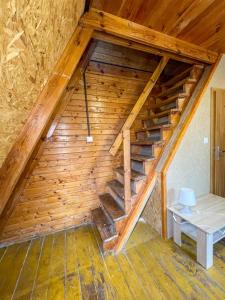 an attic with a wooden staircase in a cabin at Przygoda nad Wartą in Burzenin