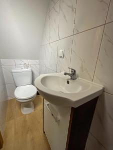 a white bathroom with a toilet and a sink at Przygoda nad Wartą in Burzenin