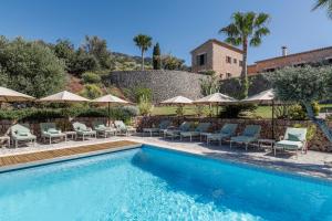 a swimming pool with chairs and umbrellas at Son Bunyola Resort and Villas in Banyalbufar