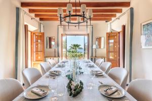 a dining room with a long table and white chairs at Son Bunyola Resort and Villas in Banyalbufar
