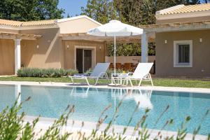 two chairs and an umbrella next to a swimming pool at Villa Botanica in Kassiopi