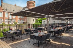 a row of tables and chairs with umbrellas on a deck at Van Der Valk Sélys Liège Hotel & Spa in Liège