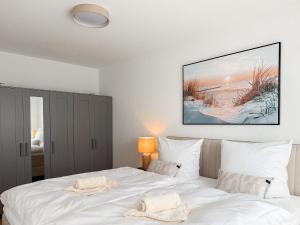 a bedroom with a white bed with a painting on the wall at Ferienwohnung Uferchalet am Dümmer See in Lembruch