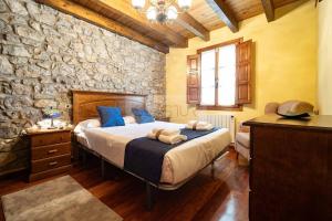 a bedroom with a bed and a stone wall at Fuente Buelna By Silastur in Buelna