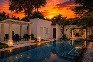 a swimming pool in front of a house with a sunset at Sunshine Beach Villa Mai Khao in Mai Khao Beach