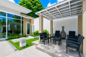 a patio with black chairs and a pergola at Sunshine Beach Villa Mai Khao in Mai Khao Beach