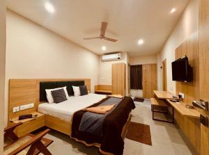 a bedroom with a bed and a desk and a television at Hotel Sree Kanya Inn in Visakhapatnam
