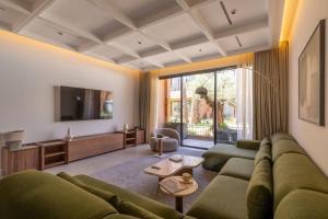a living room with a green couch and a tv at TRIANON Résidence Hôteliere in Marrakesh