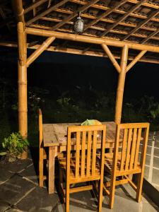 a wooden table and chairs under a wooden pergola at Tuka Cabins in Jatiluwih