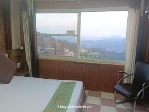 a room with a bed and a window and a chair at HOTEL MALOOK A blink away from Mall Road in Shimla