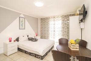 a bedroom with a bed and a desk and a television at House Goran in Crikvenica
