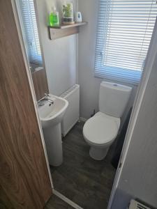 a small bathroom with a toilet and a sink at 51 Denbigh 8 berth static caravan in Prestatyn +5 photos