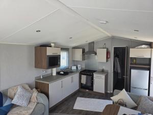 a small kitchen with white cabinets and a couch at 51 Denbigh 8 berth static caravan in Prestatyn