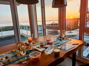 a table with food and wine glasses and a view of the ocean at Südkap H-02 in Pelzerhaken