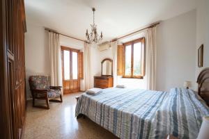 a bedroom with a bed and a chair and a chandelier at Casa Natalina in Montecatini Terme