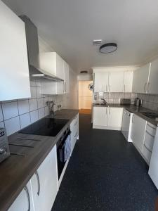 a kitchen with white cabinets and black counter tops at Home in Greatstone in Greatstone