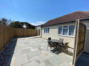 a patio with a table and chairs and a fence at Home in Greatstone in Greatstone
