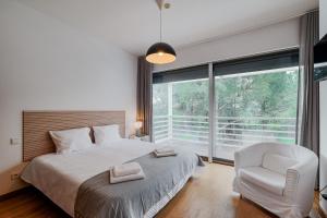 a bedroom with a bed and a chair and a window at Ocean Village Eden in Troia