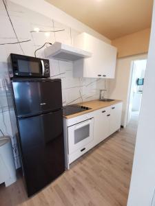 a kitchen with a black refrigerator and white cabinets at Hotel Art Balkanhof in Gelsenkirchen