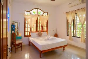 a bedroom with a bed and a chair and windows at Lakshmi Ayurveda Retreat in Kovalam