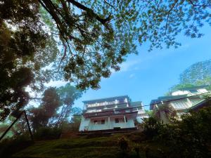 a building in the middle of a yard with trees at The Grand Hanthana in Kandy