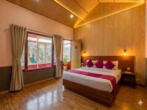 a bedroom with a large bed with red pillows at Aurevelle Kastura Resort Kanatal - Mountain View Rooms in Kanatal
