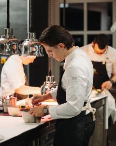 a man standing in a kitchen preparing food at Domaine de Dolomieu Hotel & Spa - BW Premier Collection in Dolomieux