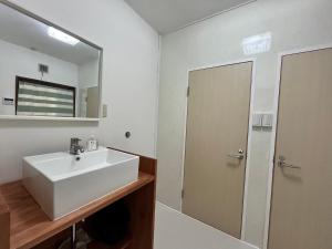a bathroom with a white sink and a mirror at Island Base Shimami in Nobeoka