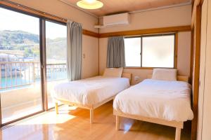 two beds in a room with a balcony at Island Base Shimami in Nobeoka