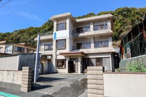 a building on a hill with a mountain in the background at Island Base Shimami in Nobeoka